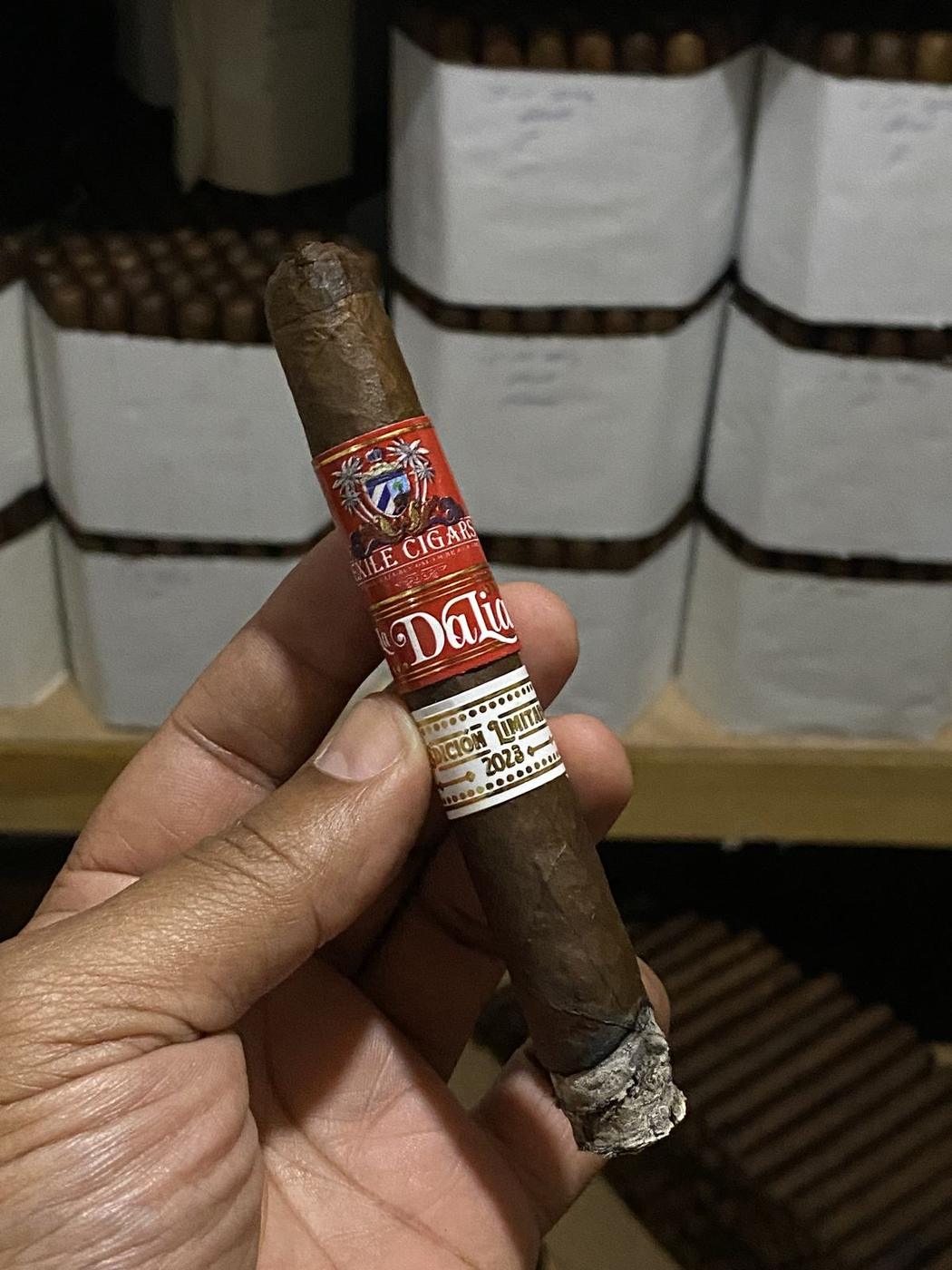 A hand holding a freshly rolled Exile cigar on the factory floor at La Union Factory