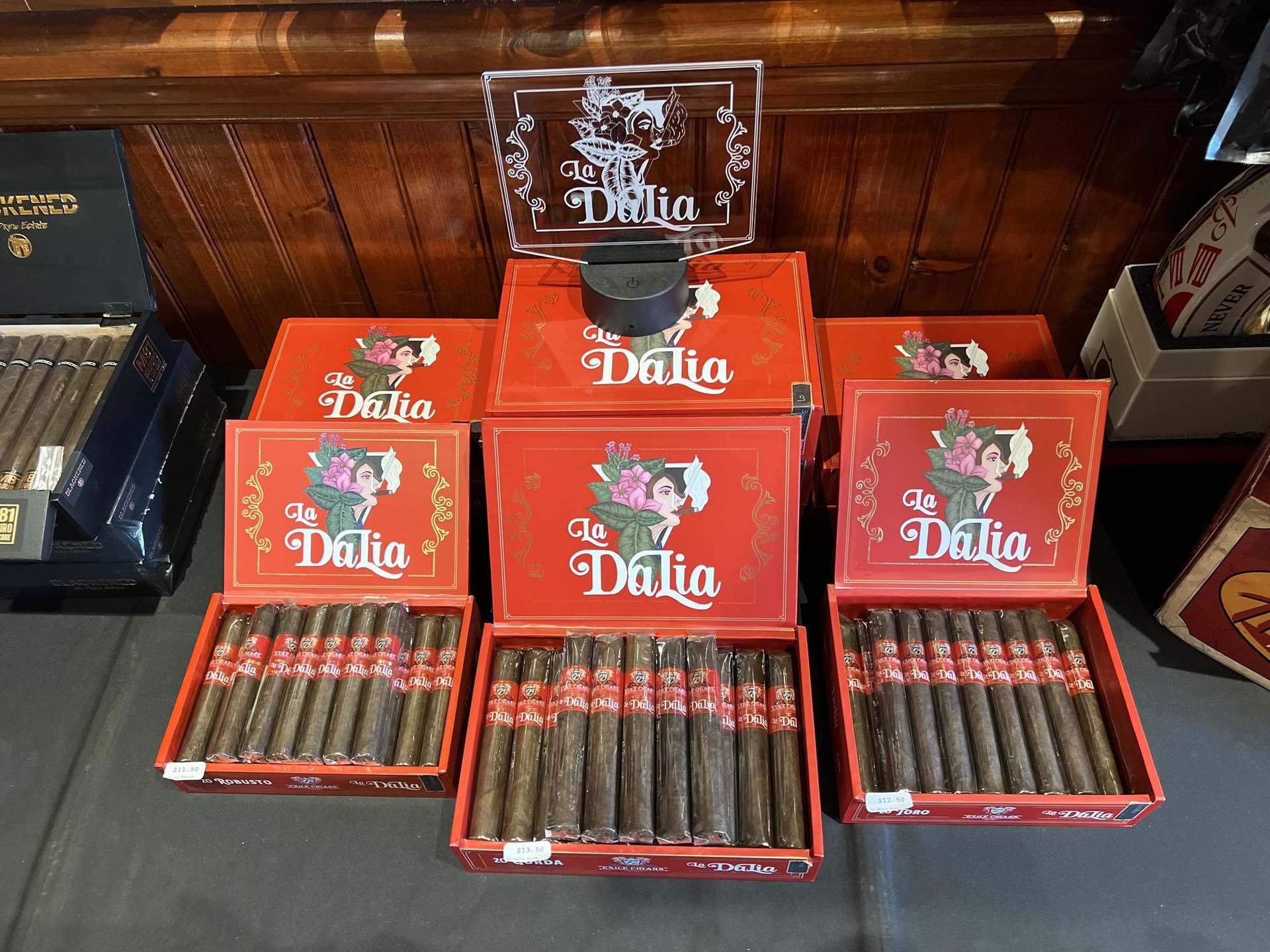 A curated arrangement of Exile Cigars boxes and hand-rolled cigars in a warm, wood-paneled retail cabinet