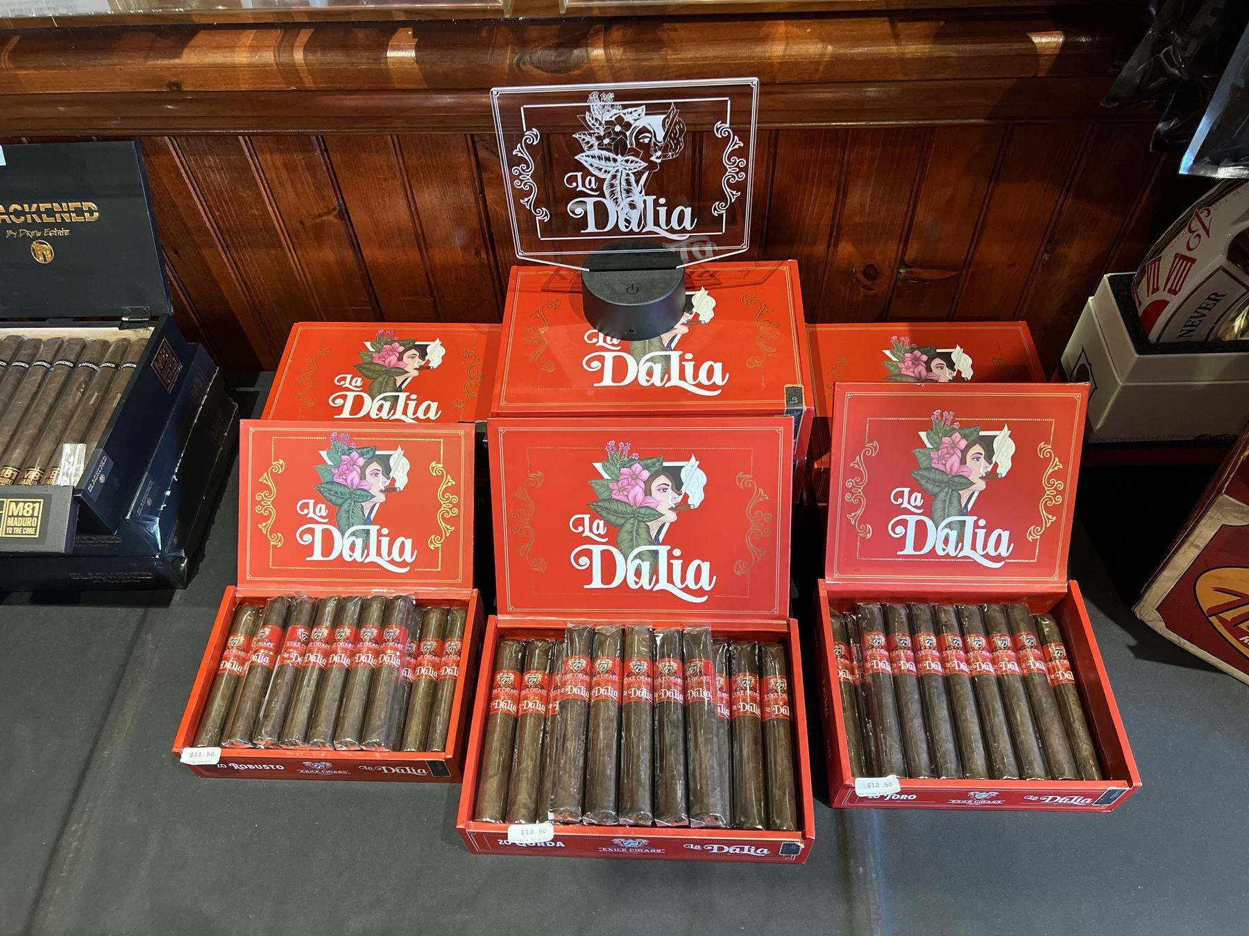An open humidor cabinet with Exile Cigars boxes displayed on wood shelving